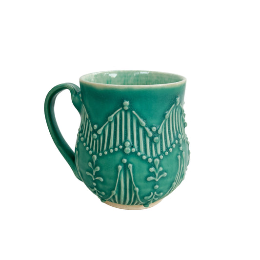 A teal/turquoise mug with zig zag pattern